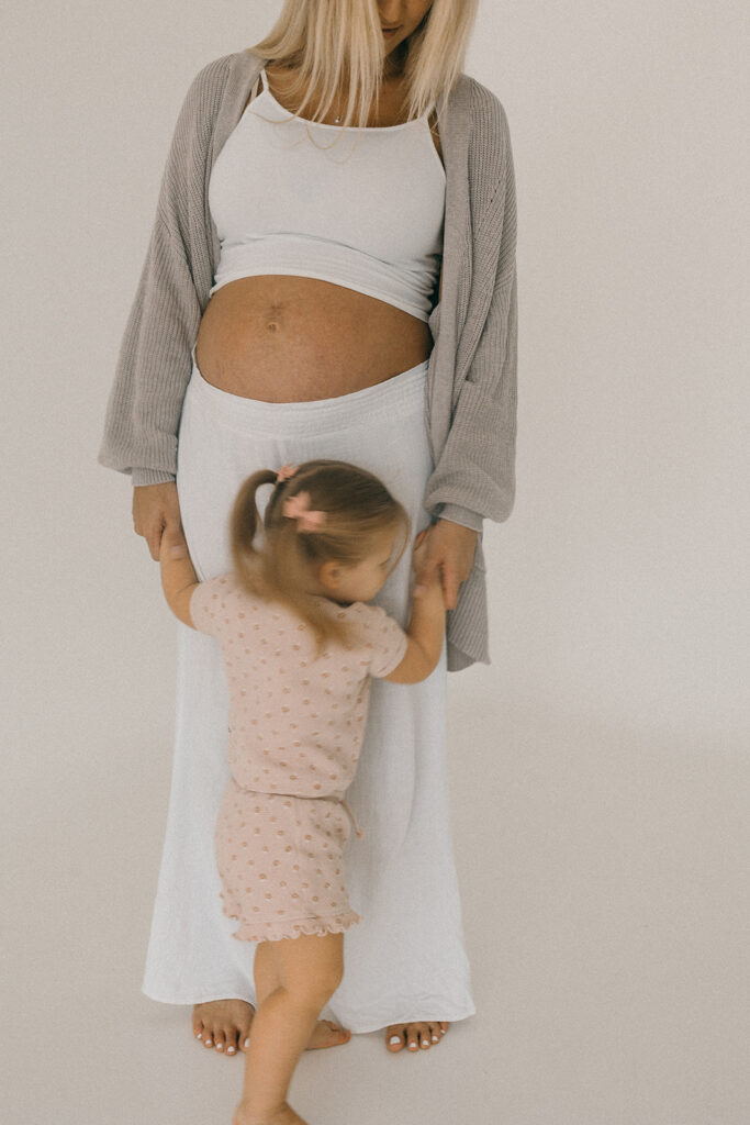 Pregnant mom and daughter standing together for a maternity photo session. 