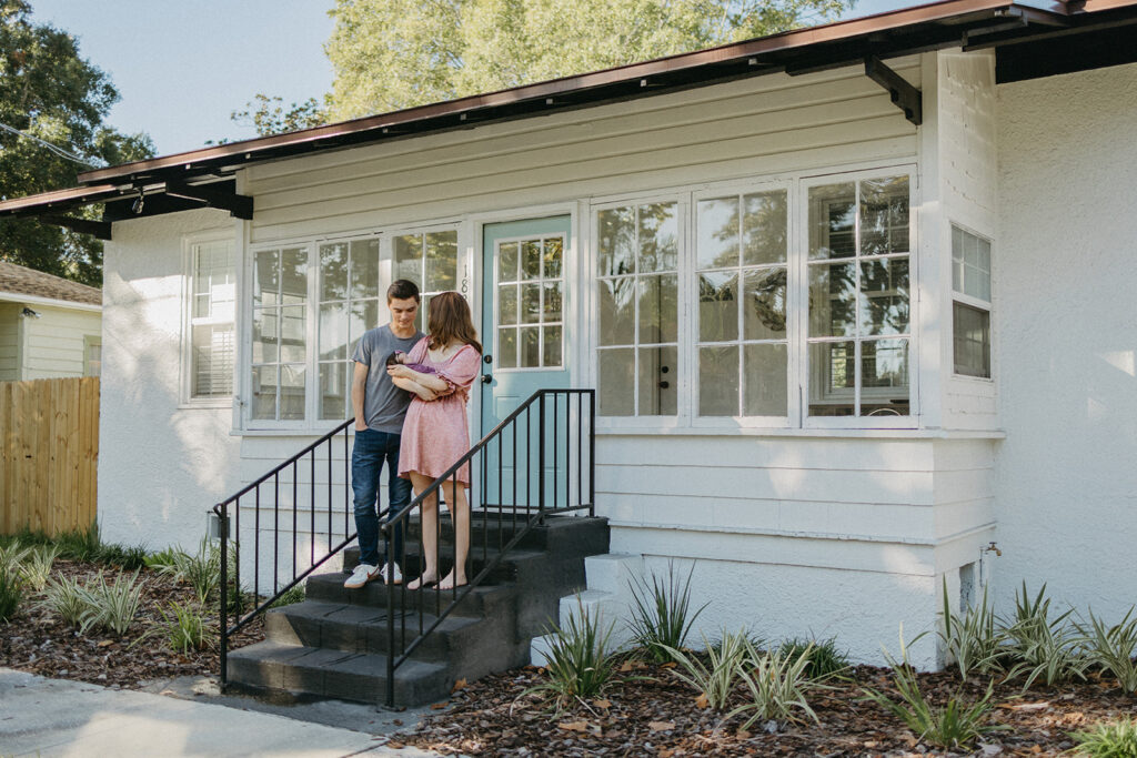 Jacksonville newborn couple standing on their porch holding their newborn baby.