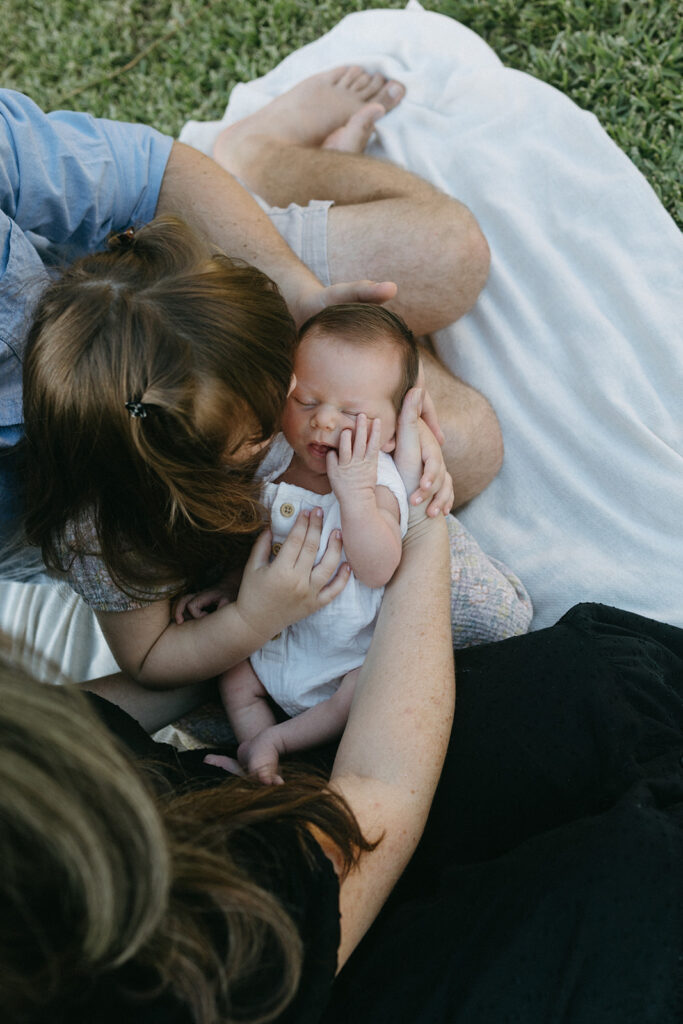 Jacksonville fl family sitting outside in the front yard cuddling the newest baby in the family