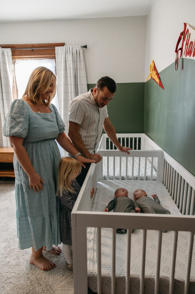 jacksonville fl family in the nursery standing over the crib admiring their baby twins