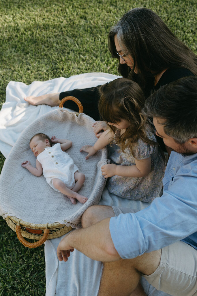 jacksonville fl family sitting outside in the front yard admiring their new baby sitting in a bassinet 