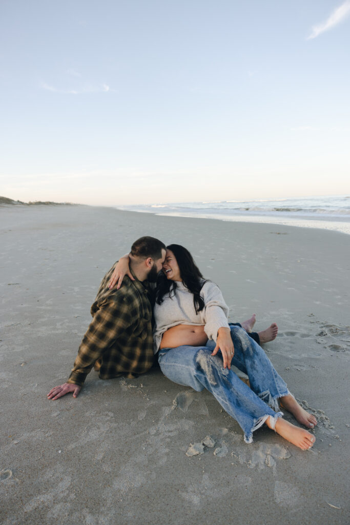 Pregnancy announcement photos in Jacksonville, Fl. Expecting parents sitting on the beach