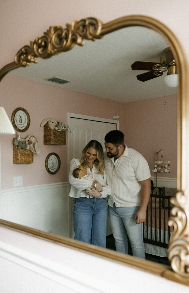 couple with their newborn baby standing together in the nursery 