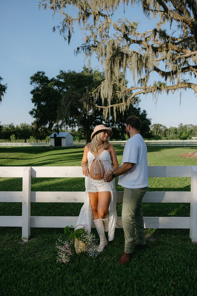 expecting couple leaning on the fence looking at eachother in jacksonville fl 