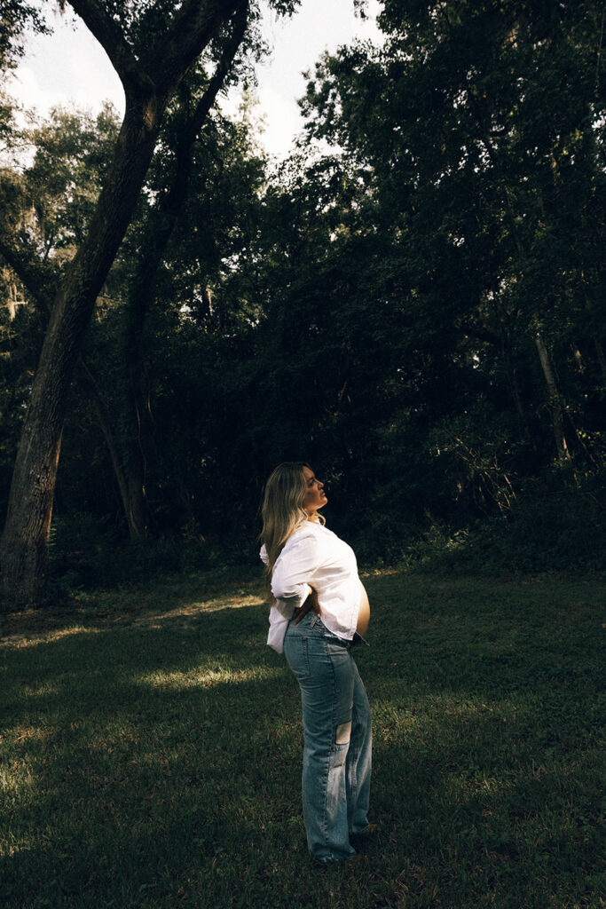 Expecting mother standing in a light casting from the sun for her editorial maternity photos in jacksonville fl